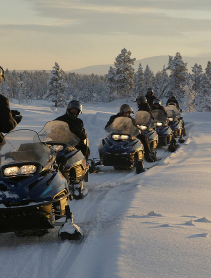 Group of people on snowmobiles in snowy setting