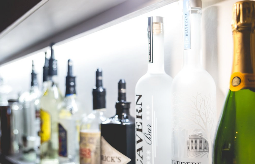 Row of alcoholic drinks bottles lined up behind bar