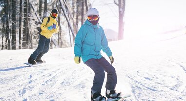 Two snowboarders in sunshine on snowy slope