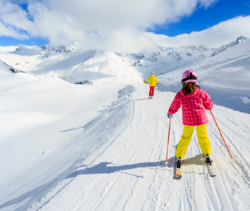Young girl skiing behind parent