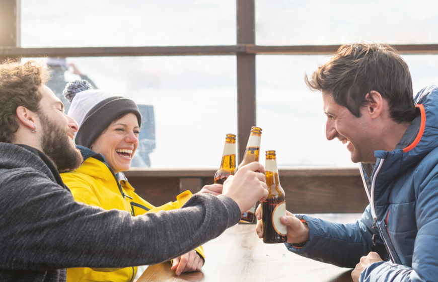 Three friends drinking beer on outdoor terrace in the winter