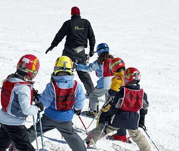 Children in ski lessons following instructor