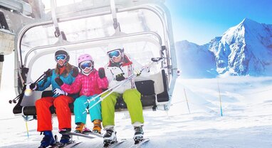 Two smiling adults and a child getting off a chairlift