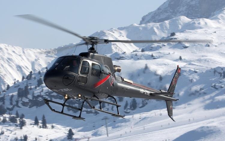 Grey and red helicopter flying in mountains