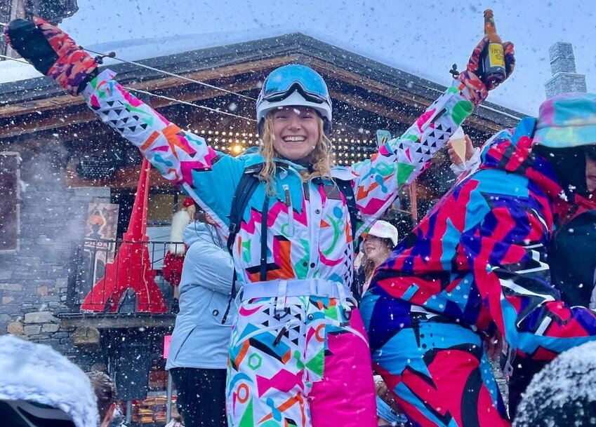 Girl dancing in ski kit with beer in hand
