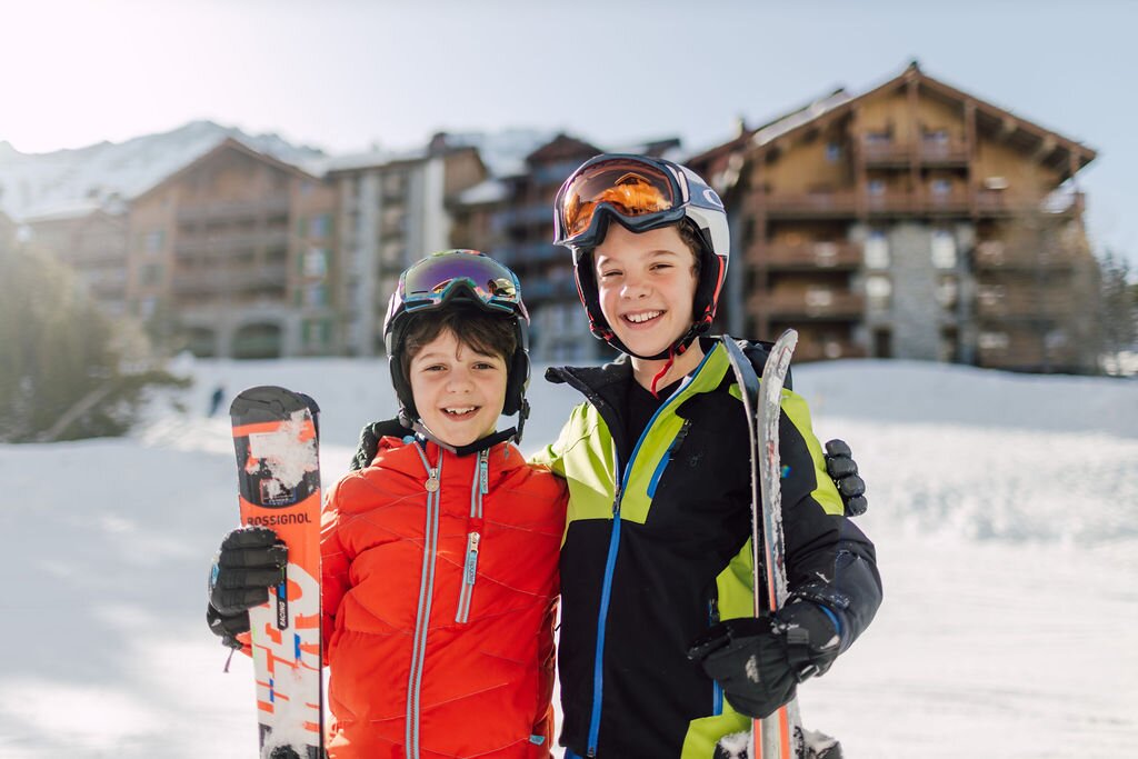 Two smiling boys standing with skis outside Bear Lodge in Arc 1950