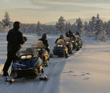 Line of people on snowmobiles at the end of the day