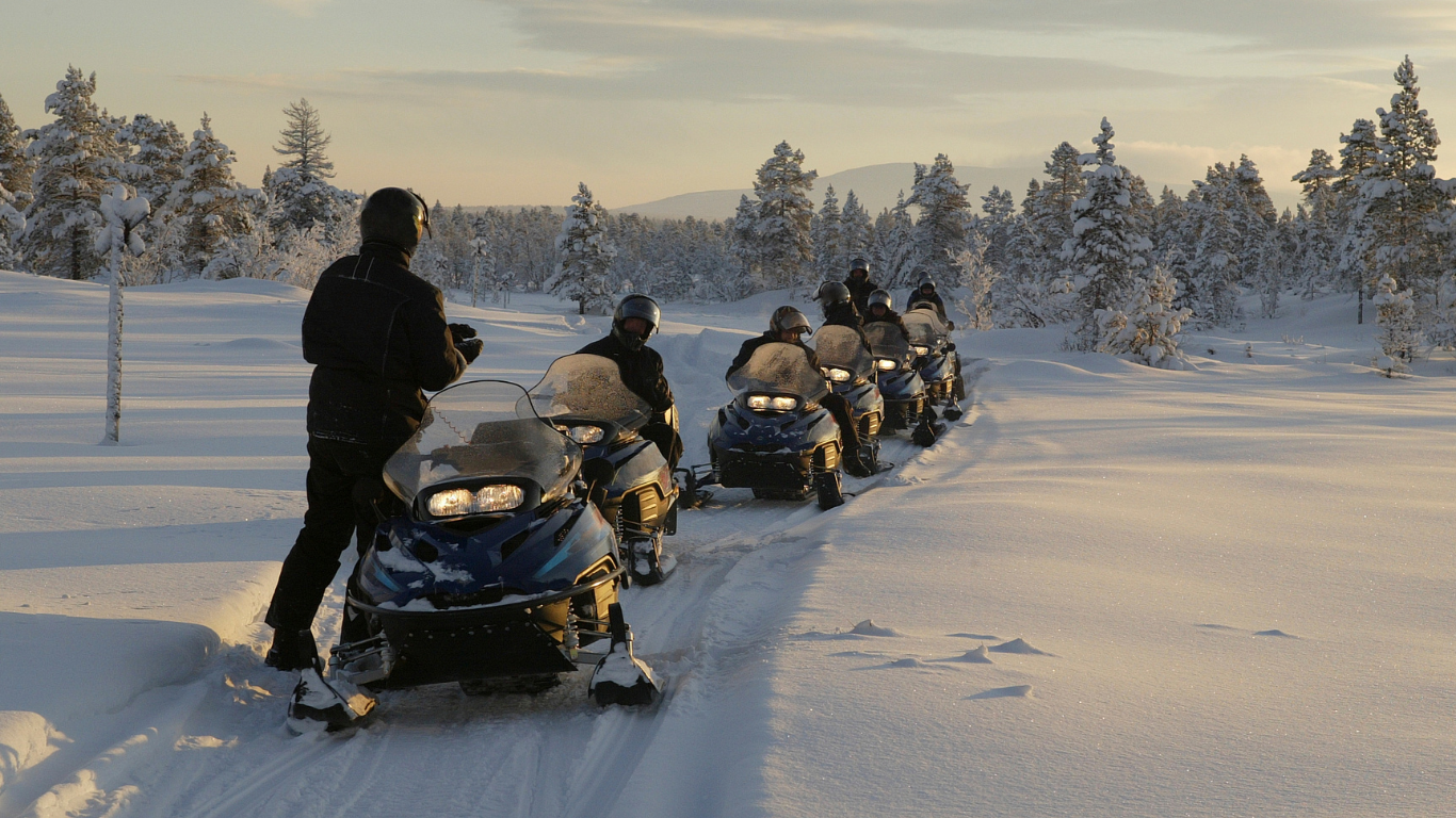 Group of people on snowmobiles in snowy setting