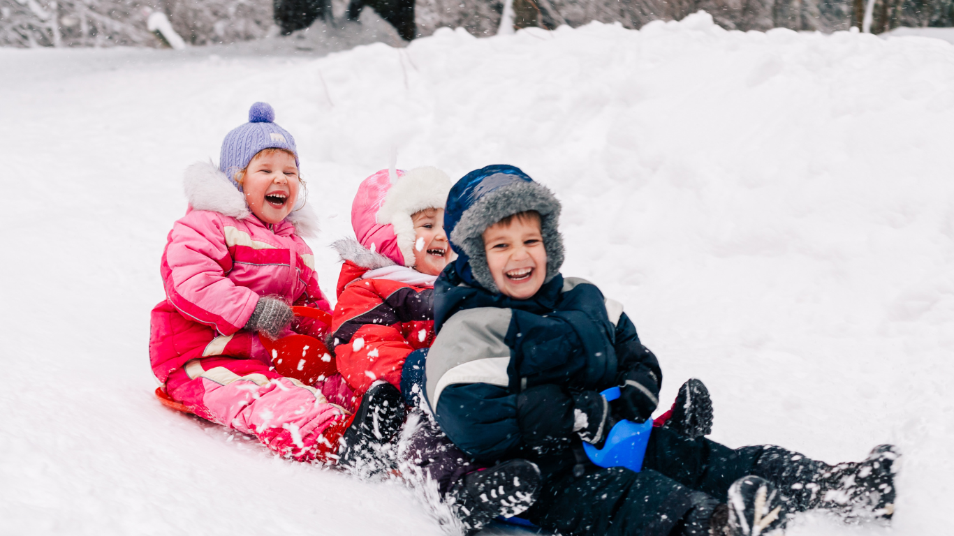 Three smiling children sledging