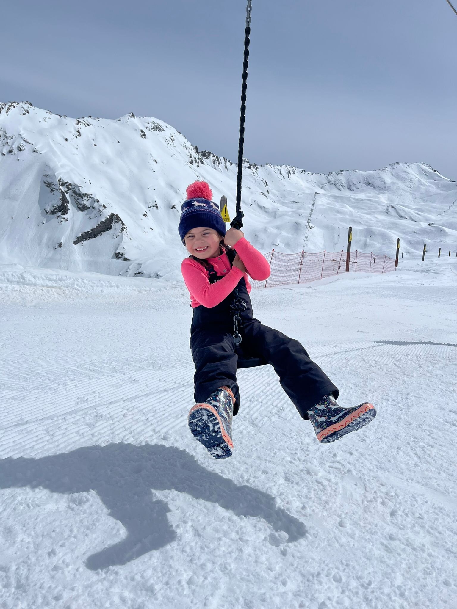 Young girl on a ski holiday swinging over the snow