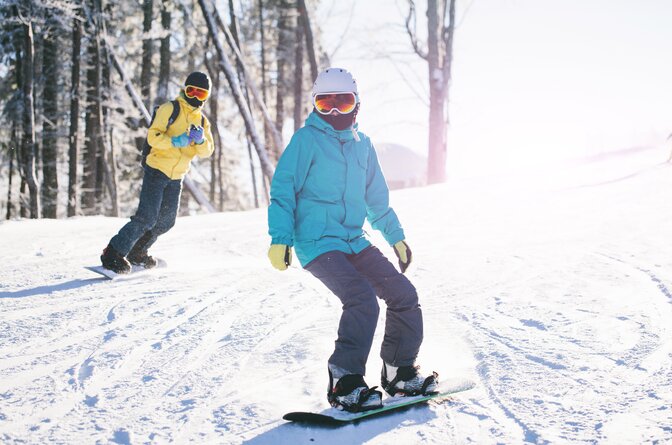 Two snowboarders in sunshine on snowy slope