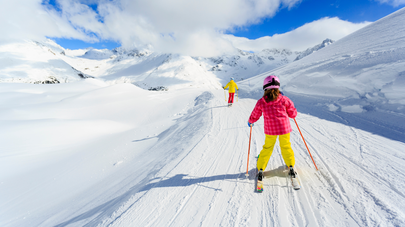 Young girl skiing behind mother