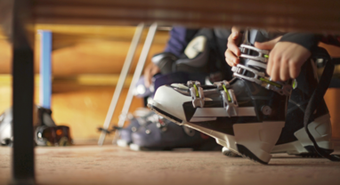 Skier doing up ski boots in boot room