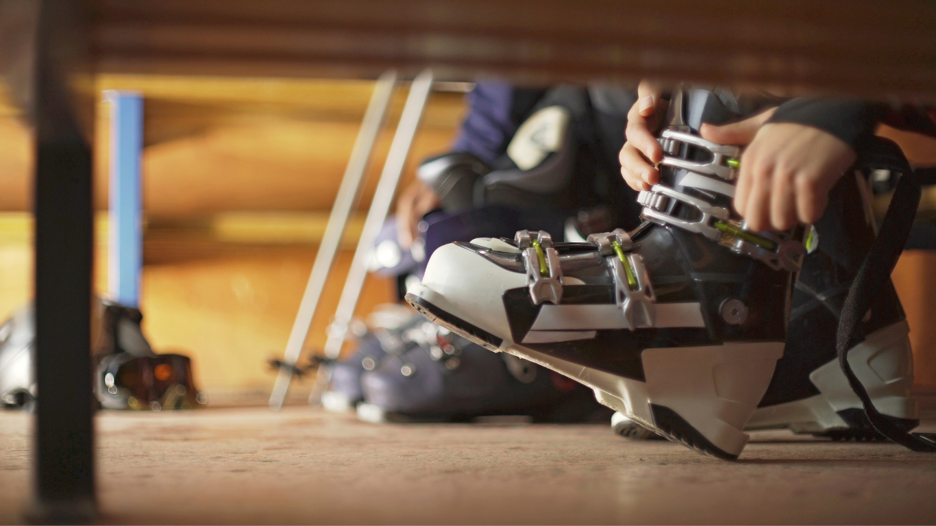 Person doing up ski boots in ski boot room