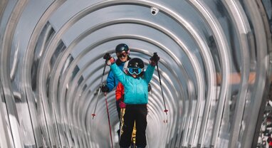 Child coming up magic carpet ski lift with poles in the air