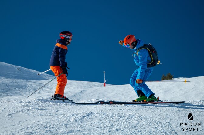 Maison Sport ski instructor teaching child to ski on sunny day