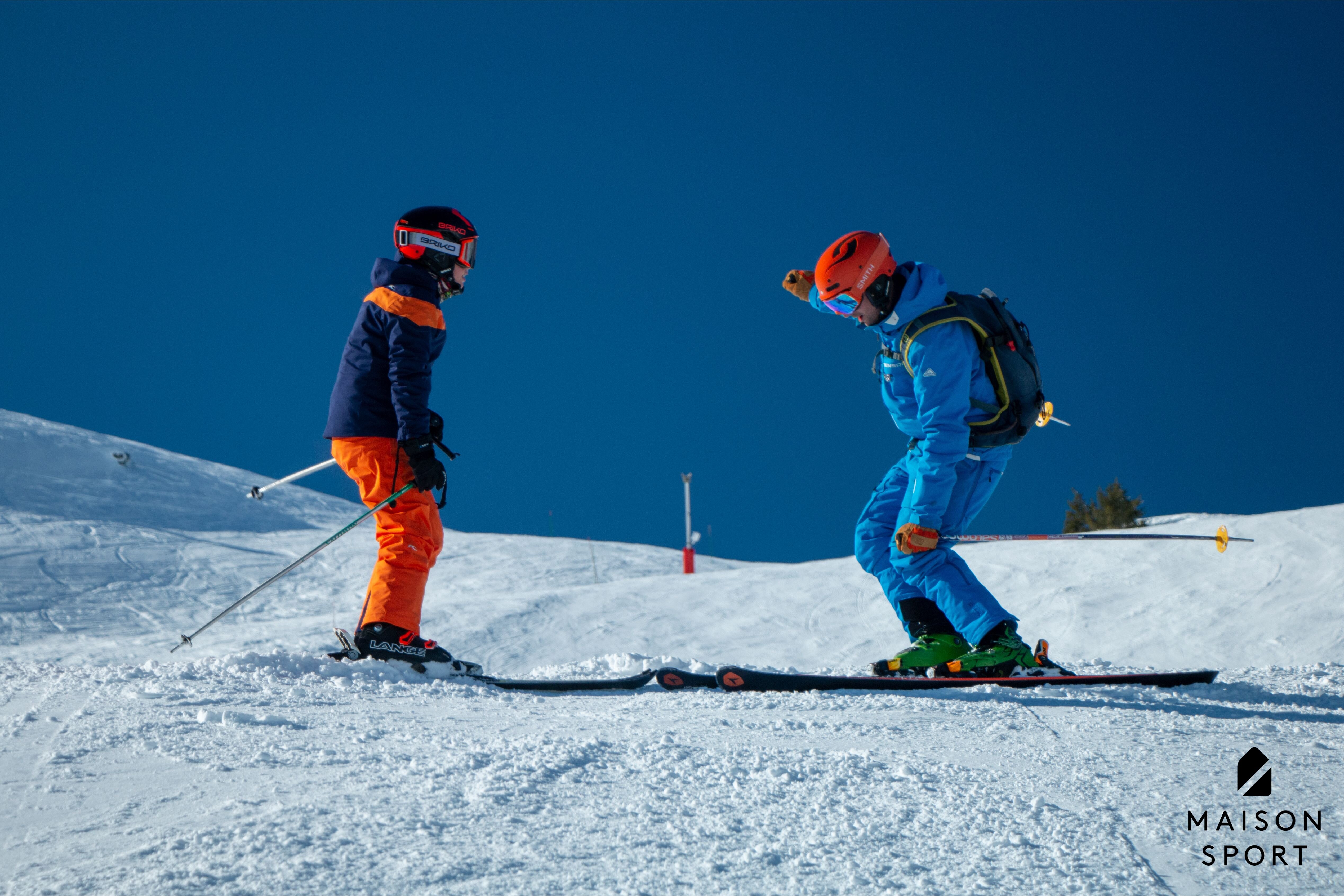 Maison Sport ski instructor teaching child to ski on sunny day