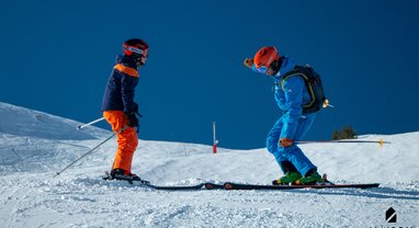 Maison Sport ski instructor teaching child to ski on sunny day