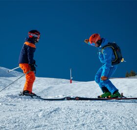 Maison Sport ski instructor teaching child to ski on sunny day