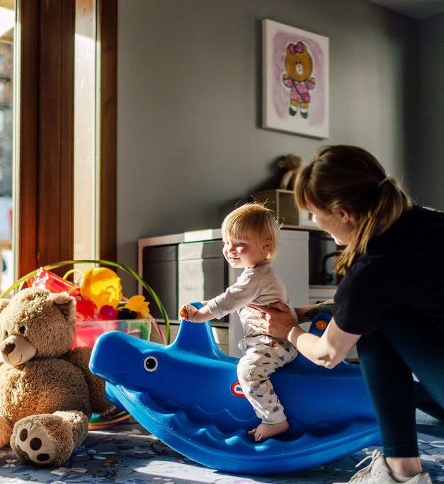 Smiling toddler on ride on toy with nanny at Bear Cubs