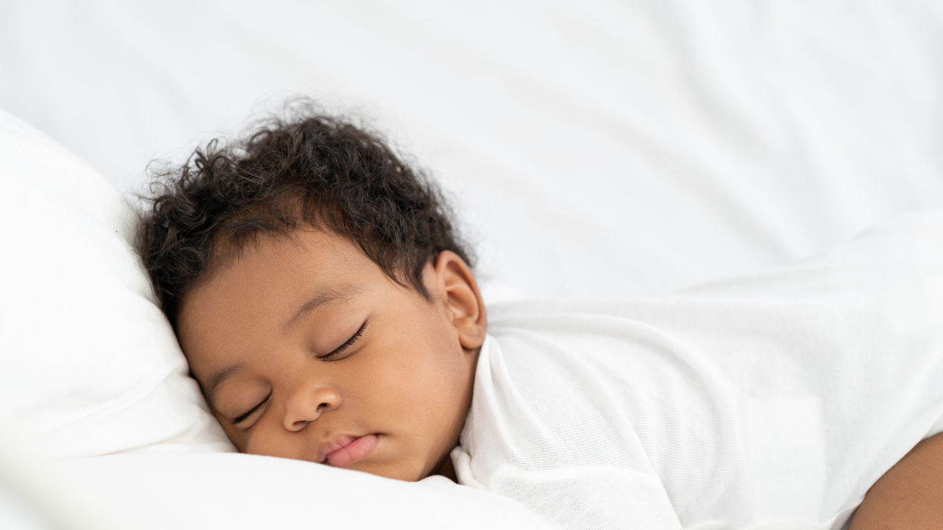 Image of sleeping baby on white bed sheets