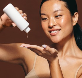 Smiling woman pouring skincare product out of bottle onto hand