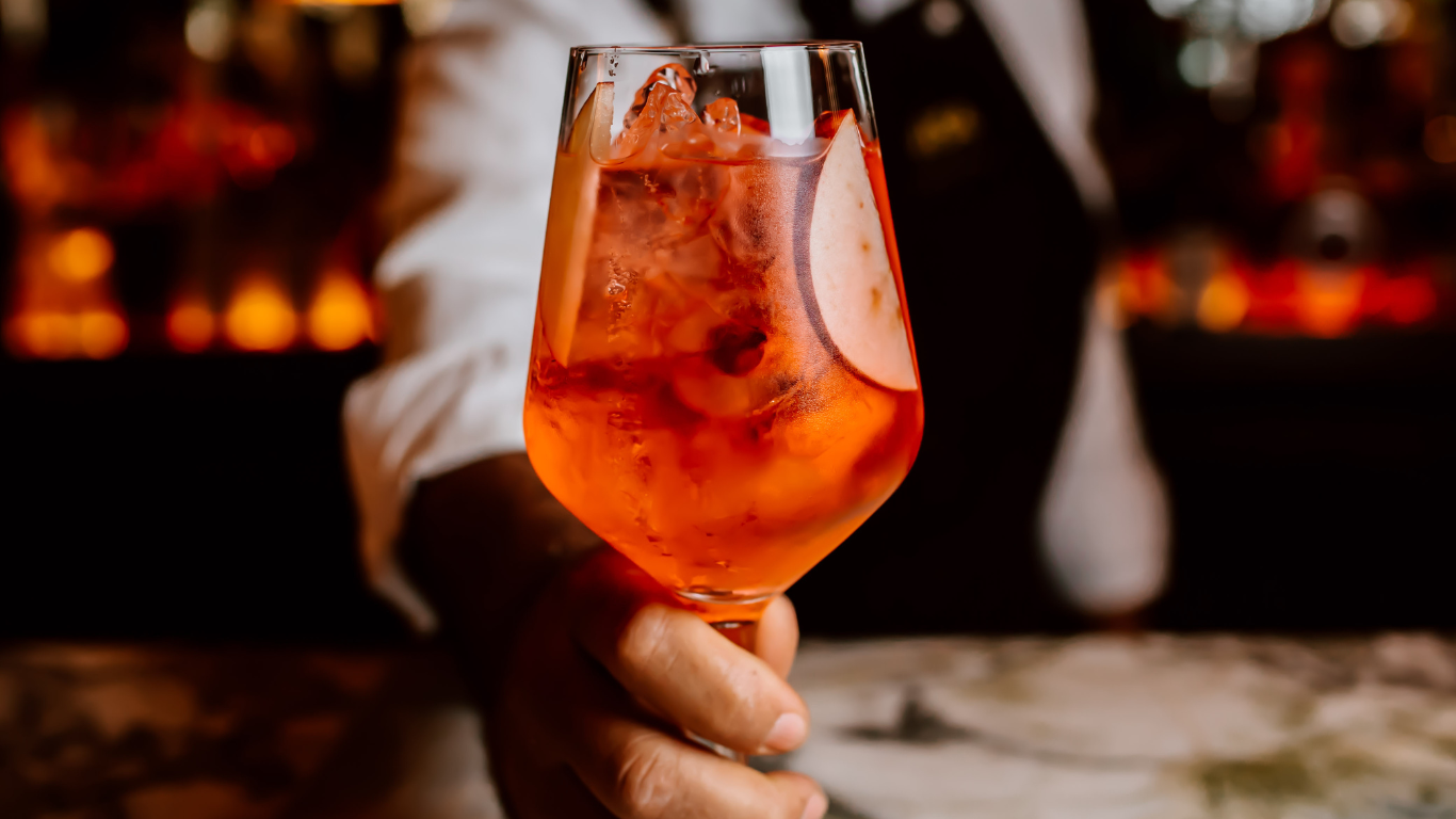 Closeup of Aperol Spritz being served by bar man in elegant bar