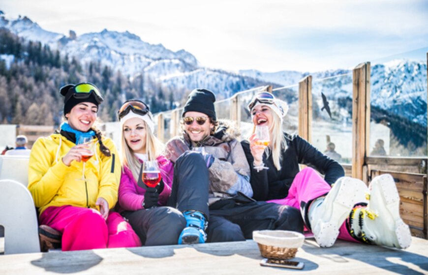 Four friends enjoying an après-ski drink on outdoor bar terrace
