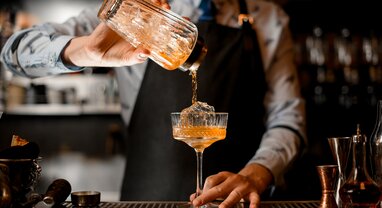 Orange cocktail being poured by barman