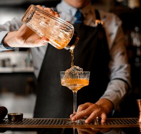 Orange cocktail being poured by barman