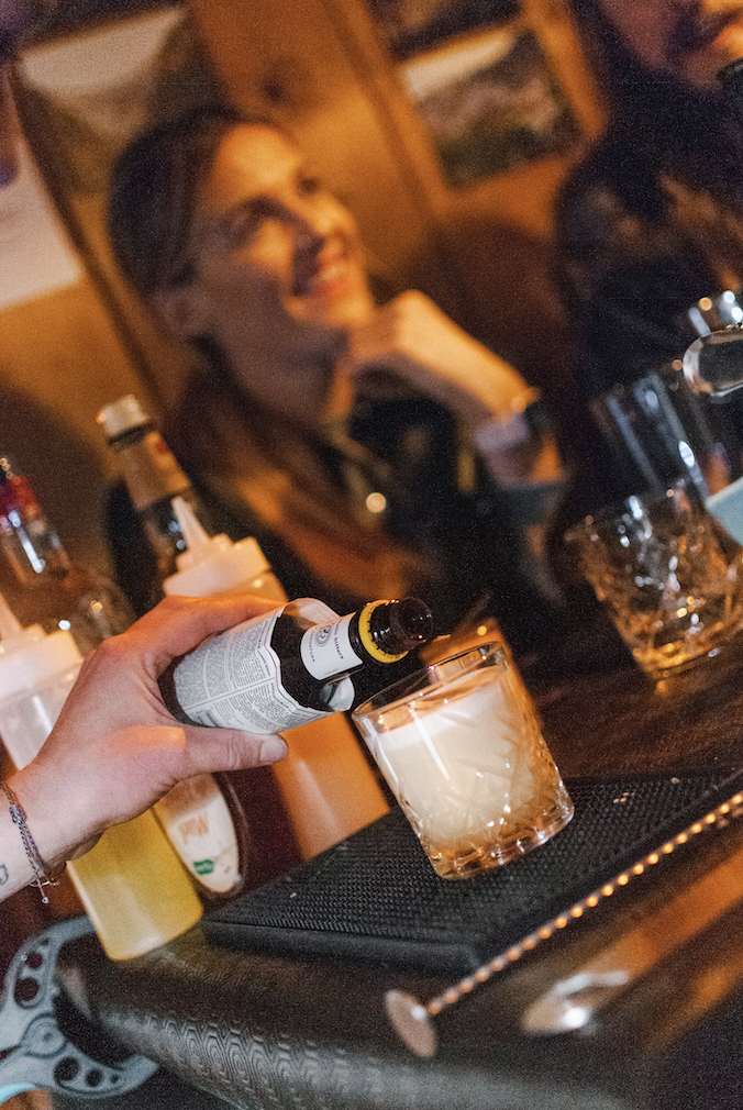 Hand pouring bitters into a cocktail glass