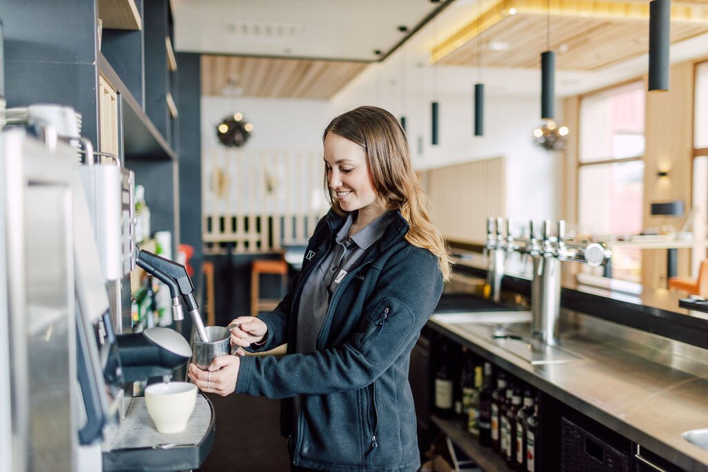 Smiling VIP SKI staff member heating milk in Bear Lodge bar