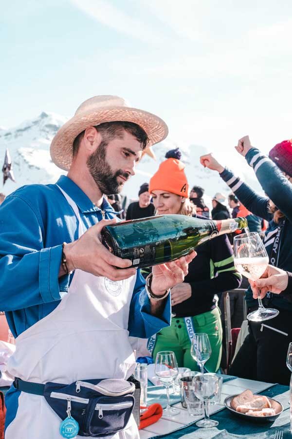 Waiter wearing sunhat pouring wine into glass on sunny terrace