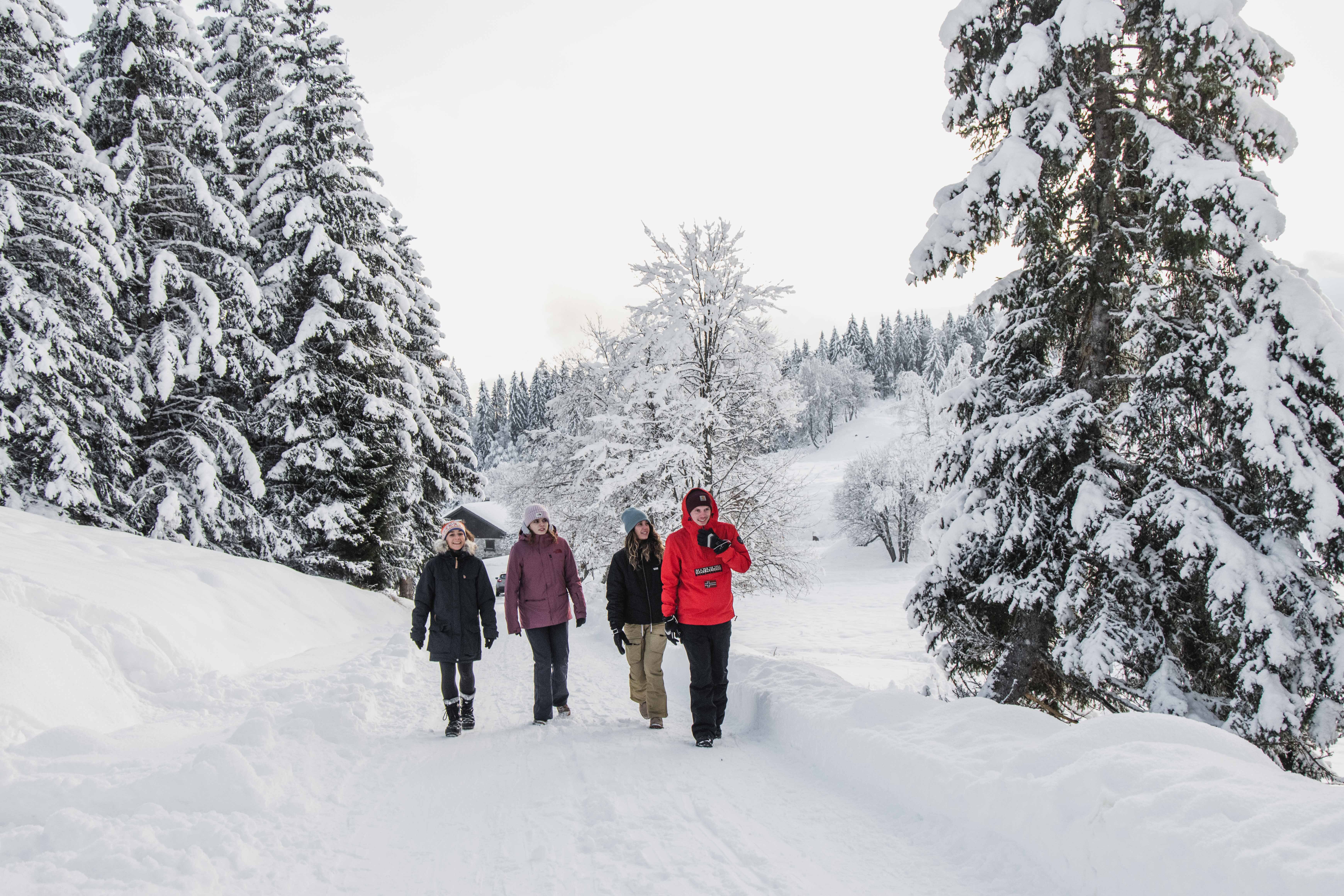 Four people walking along very snowy path in Les Gets
