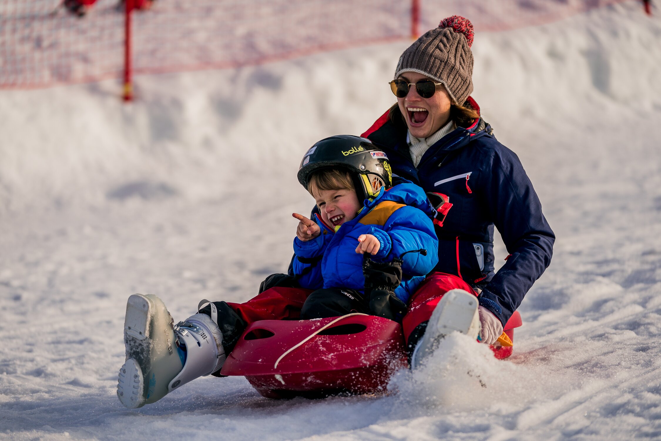 Smiling woman sledging with young son