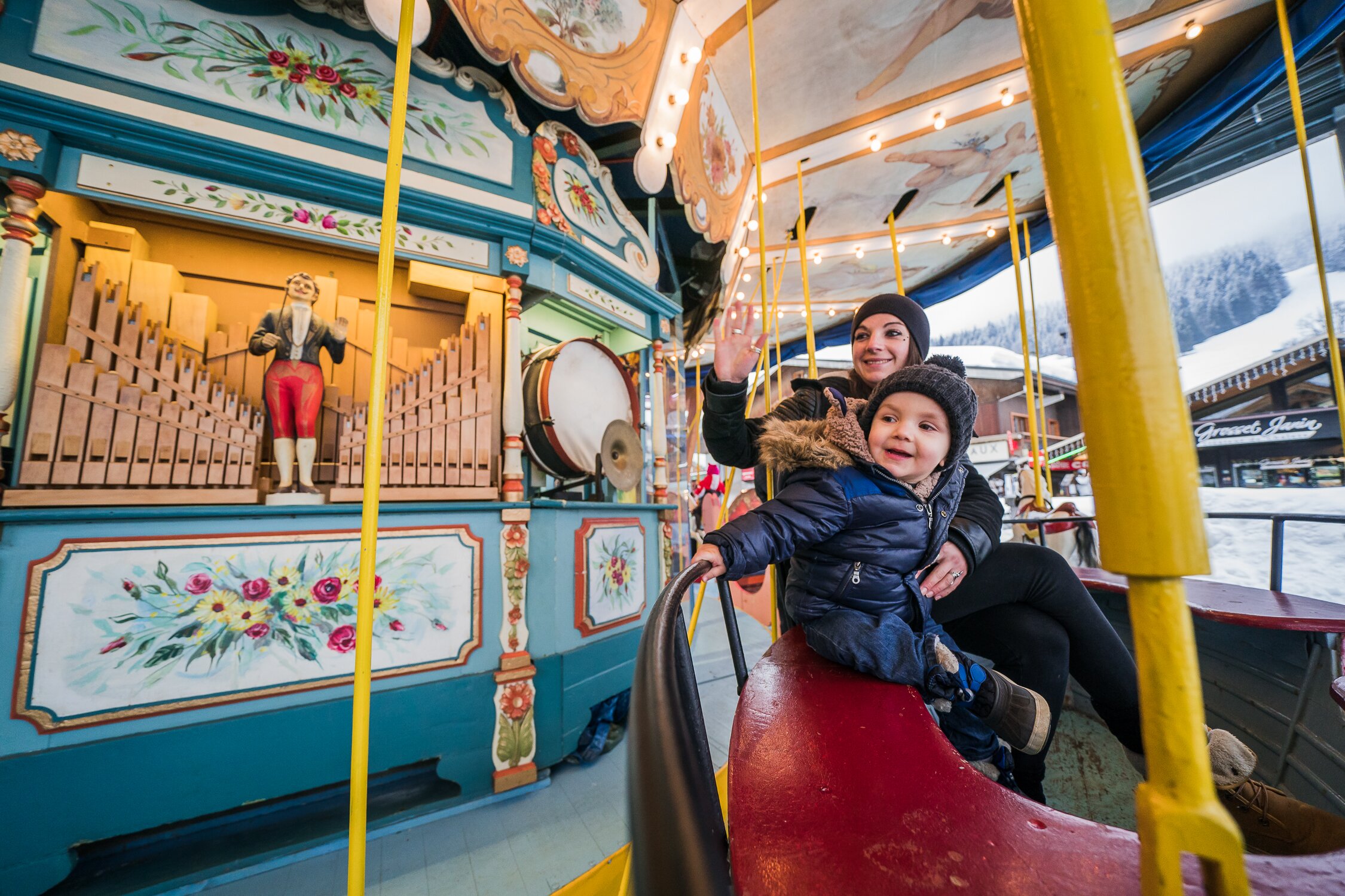 Mother and son on wooden carousel in Les Gets