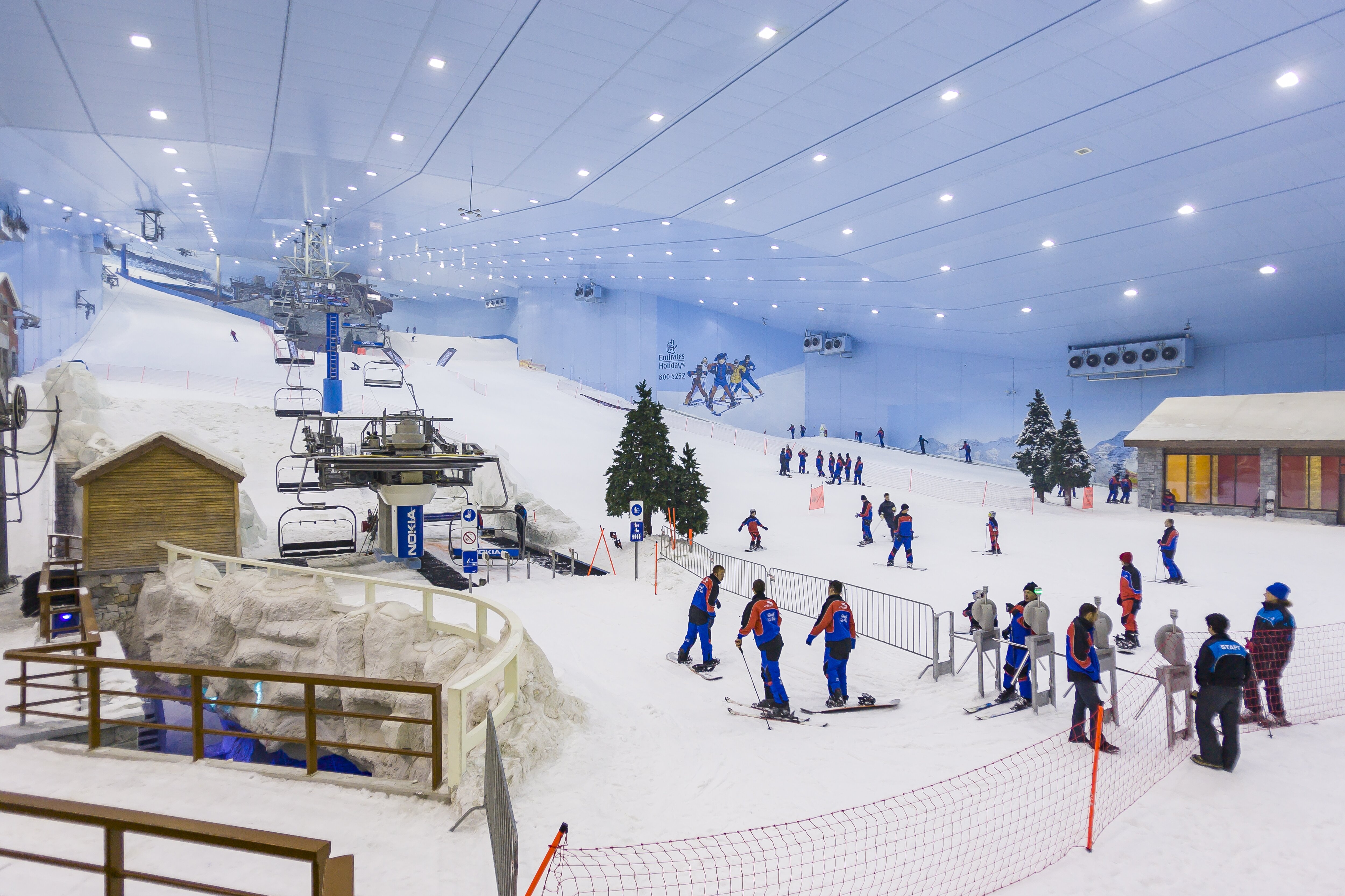 Indoor snow centre in Dubai with chairlifts and real snow and people skiing and snowboarding