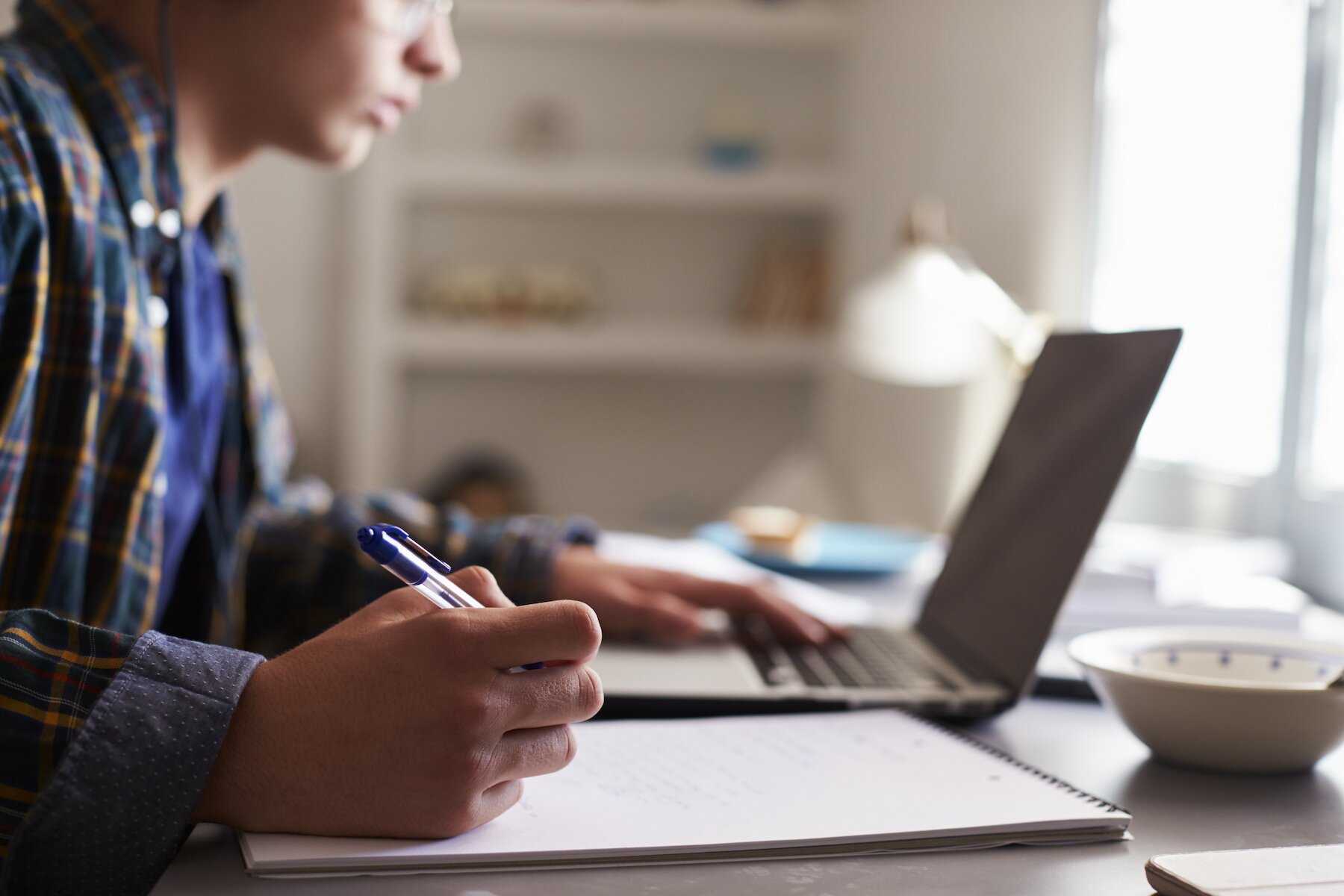 Boy with notepad working at laptop