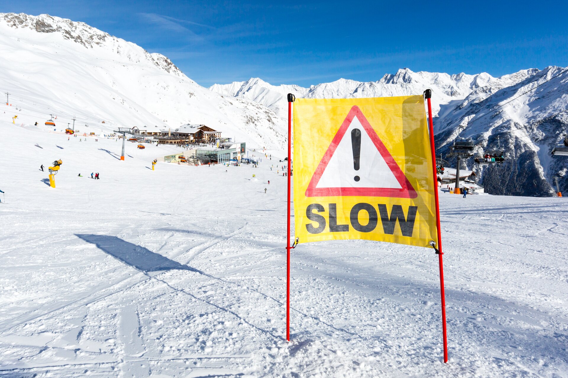 Slow sign in middle of ski slope coming down towards ski lift and mountain restaurants