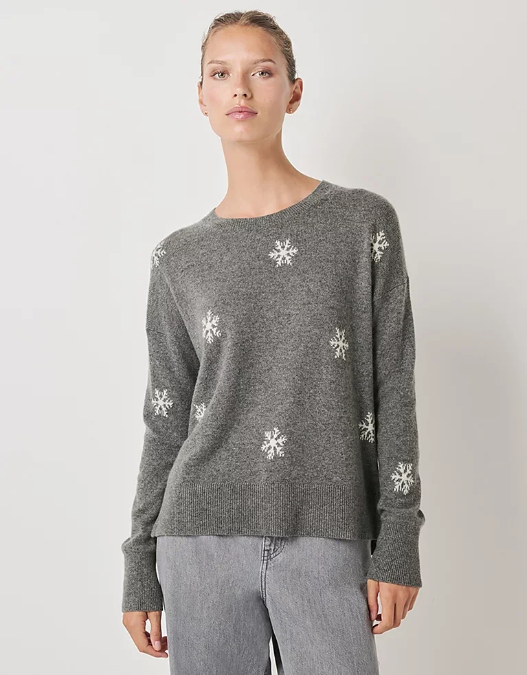 Woman wearing grey cashmere round neck jumper with white snowflakes from The White Company