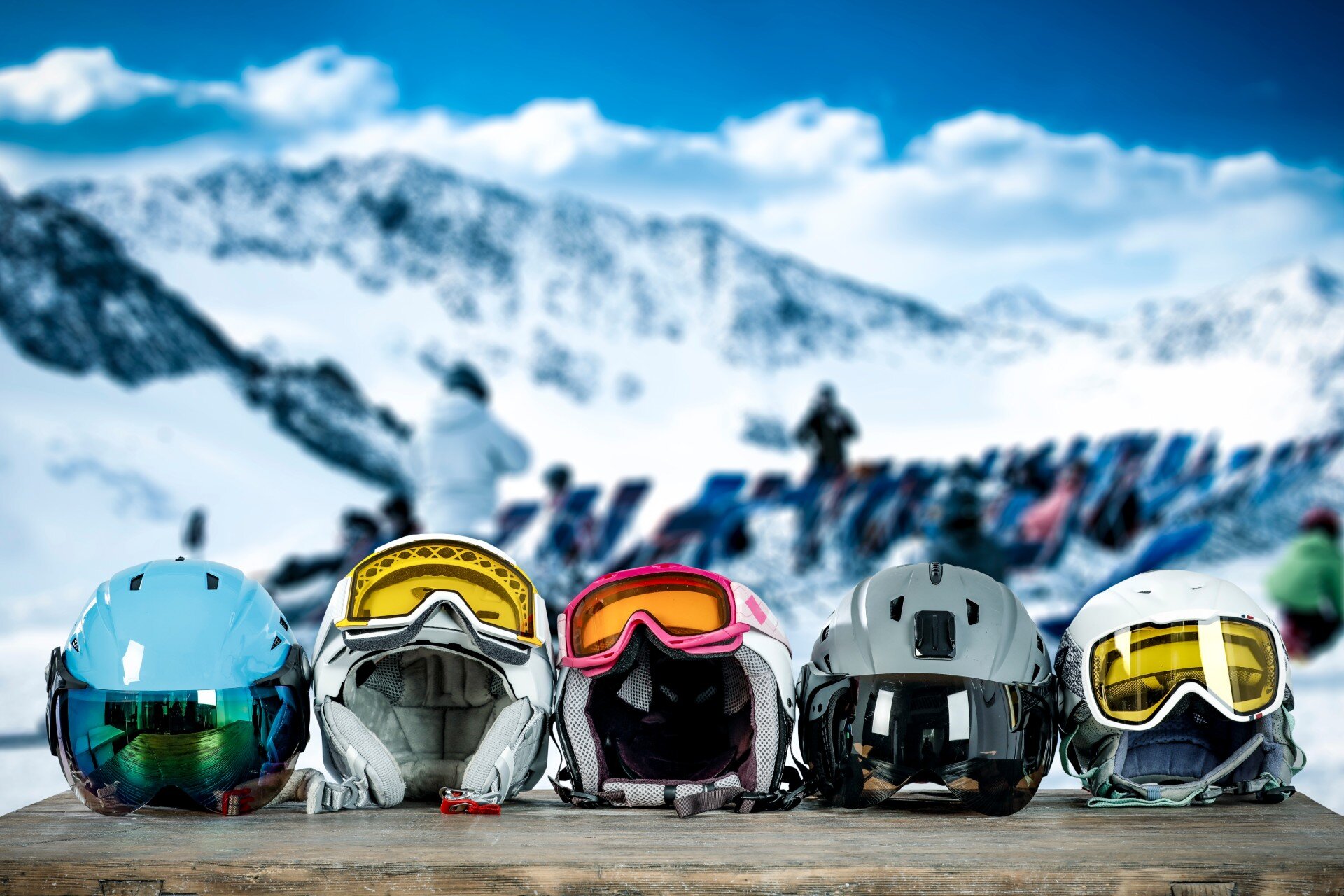 Five ski helmets with goggles lined up on a table at mountain restaurant