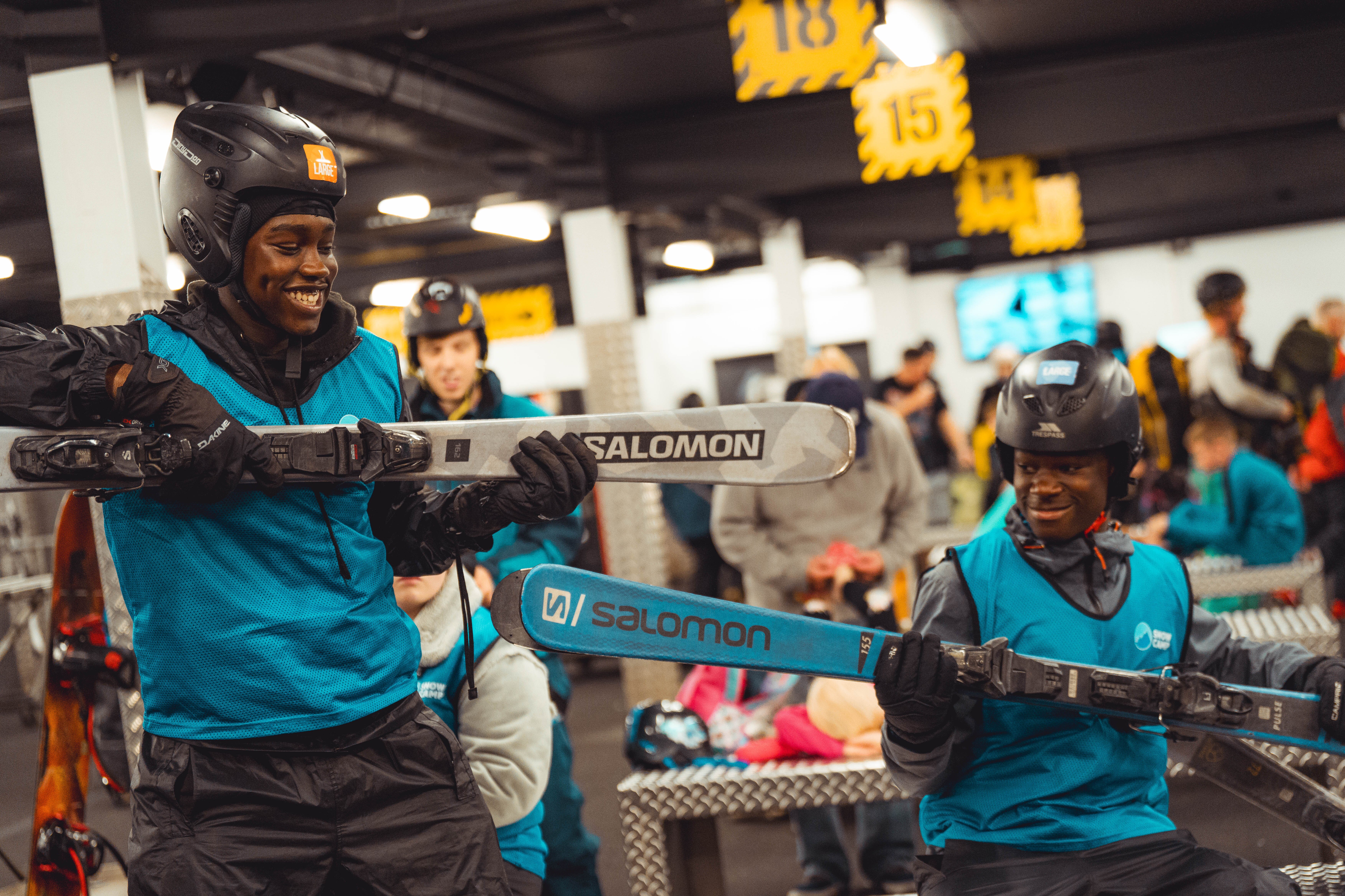 Smiling young boys holding skis in rental shop at indoor snow centre