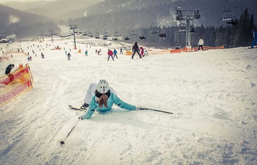 Female skier who has fallen down at the top of ski piste