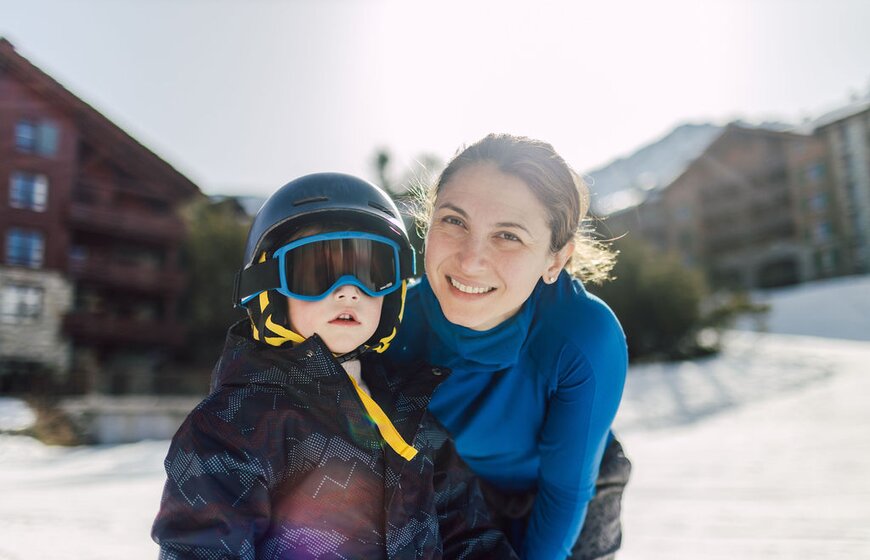 Mother and son in ski gear outside chalets in Les Arcs