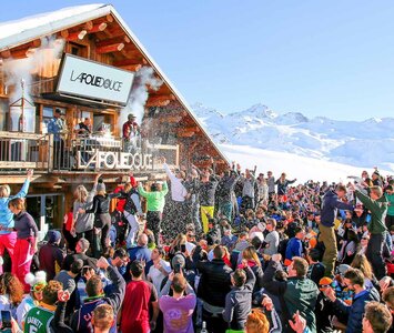 Large crowd of people dancing on terrace of La Folie Douce on a sunny day