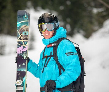Oxygene ski instructor standing holding skis