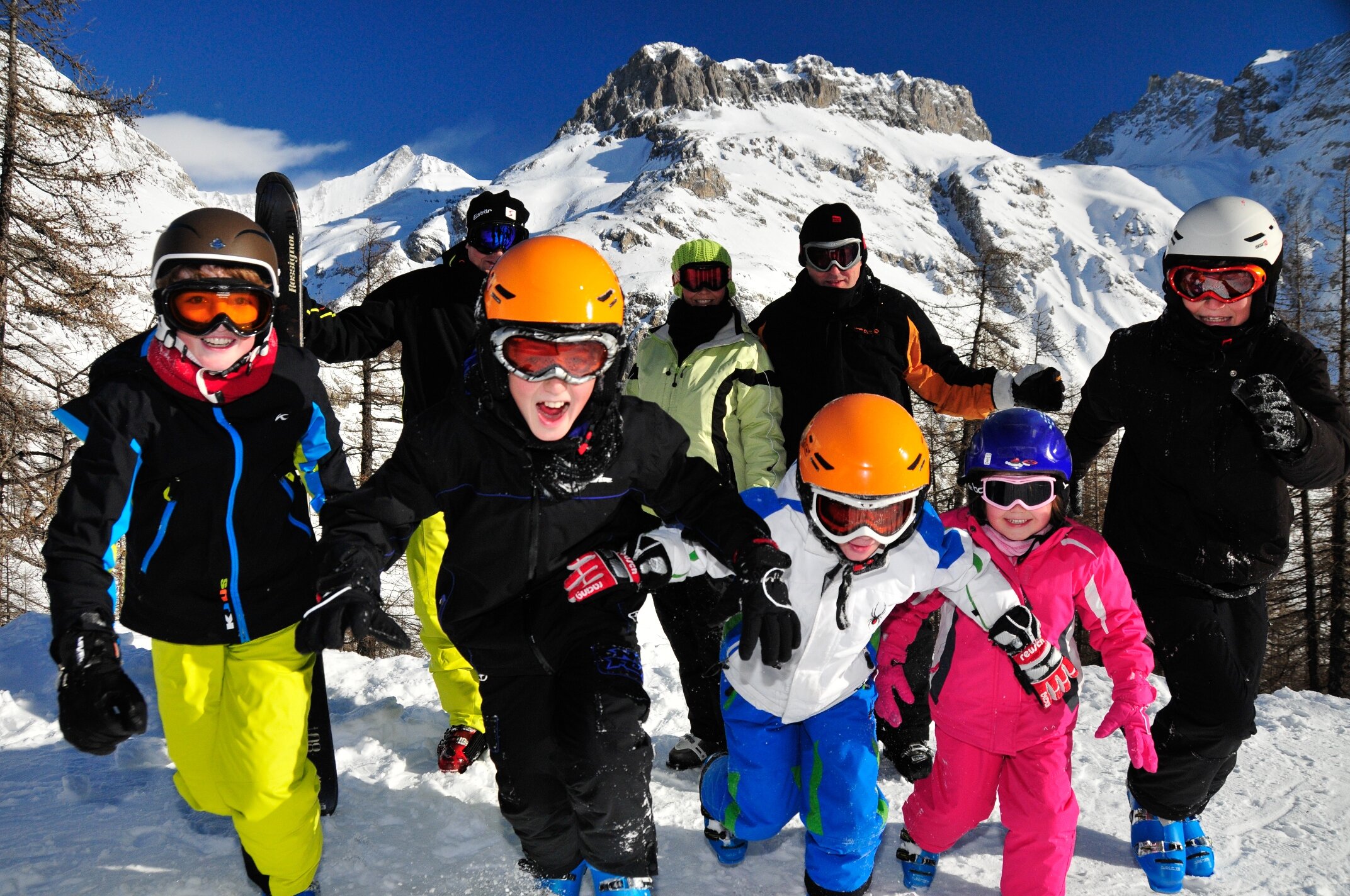 Family group in ski gear smiling and running towards camera