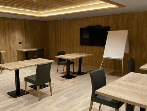 Room in chalet set up with with tables and chairs and presentation board