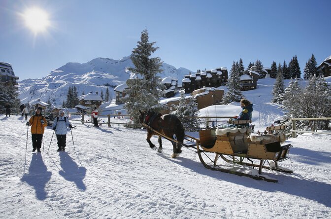 Horse-drawn sleigh and walkers in Avoriaz on sunny day