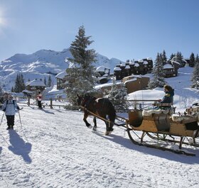 Horse-drawn sleigh and walkers in Avoriaz on sunny day